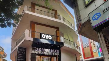 Un edificio de varios pisos con un letrero que indica 'OYO' y 'Paras Palace', señalando un hotel o espacio para eventos.