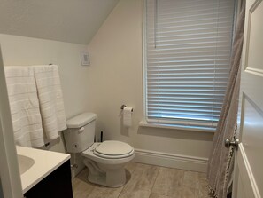 A bathroom with a toilet, sink, and window with blinds.