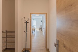 A hallway with a coat rack, a wooden door frame, and a view into a dining area with a table and chairs. - New Listing (Mainz)