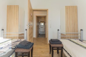 Una camera d'albergo con due letti, una panca e un tavolino.