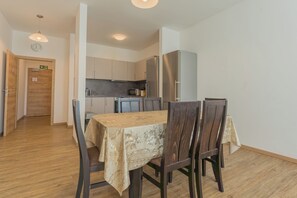 Zona pranzo con tavolo e sedie, cucina con mobili ed elettrodomestici, e pavimento in legno.