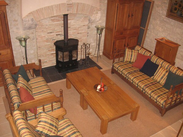 A cozy living room with a fireplace, striped sofas, and a wooden coffee table. - New Listing (Villeréal)