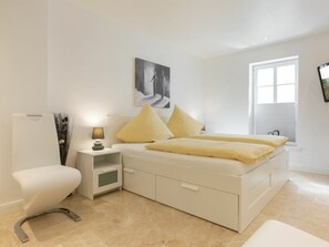 A bedroom with a bed, bedside table, lamp, and a painting on the wall. - Holiday Home in Rantum With Swimming Pool (Sylt)