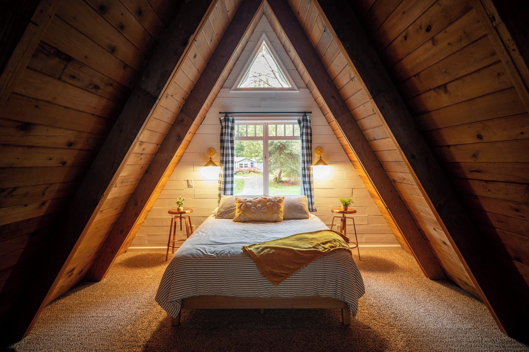 Une chambre confortable située dans les combles, avec un lit, deux tables de chevet, une fen être avec des rideaux et une vue sur l’extérieur.