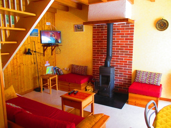 Una habitació acollidora amb un sofà, una taula petita, una televisió i una llar de foc.