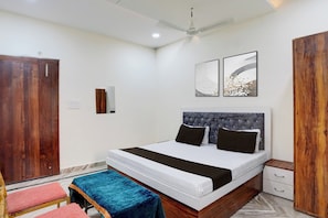 Un dormitorio con cama, mesitas de noche, un armario y una obra de arte en la pared.