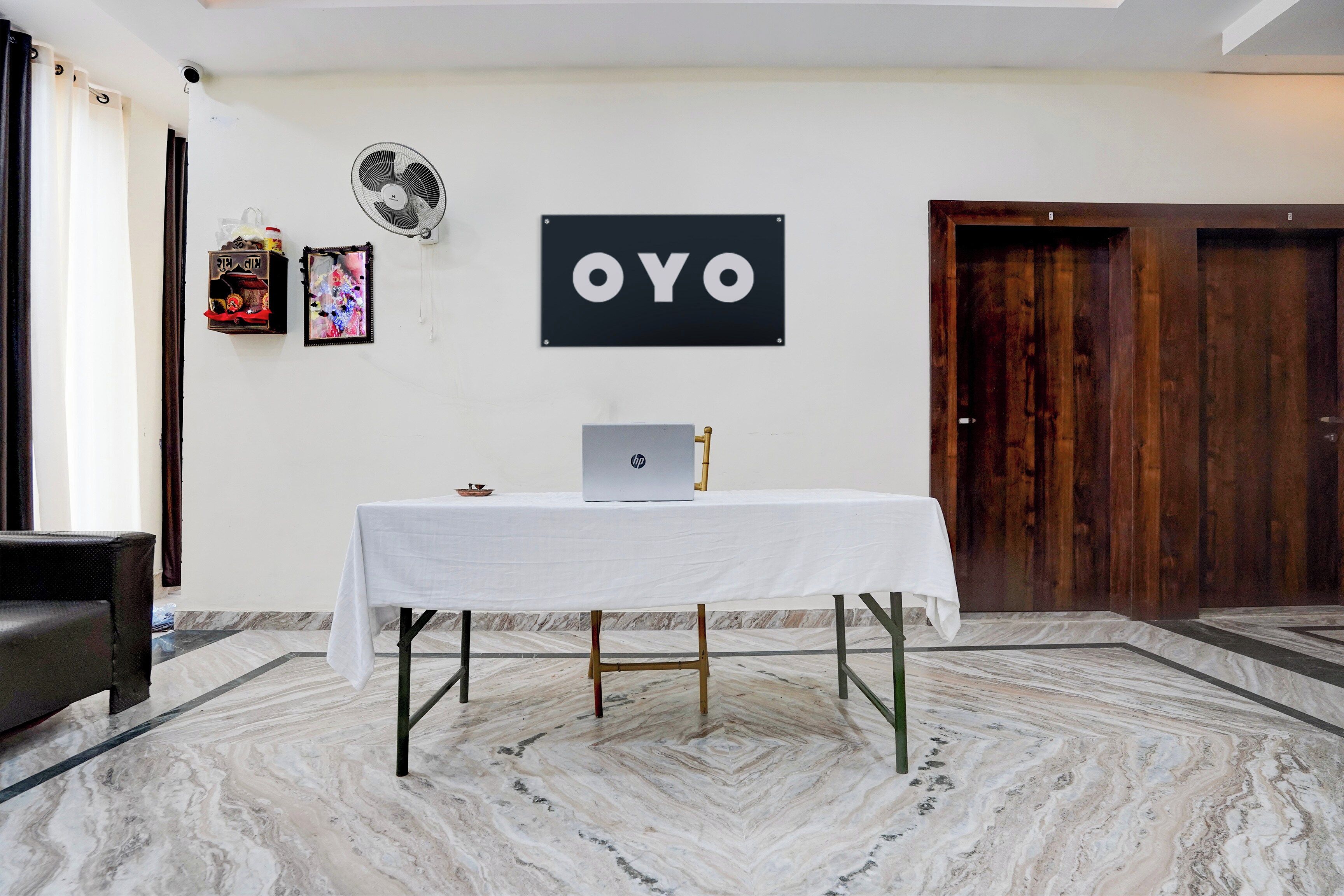 A room with a white table, a laptop, a fan, and a door.