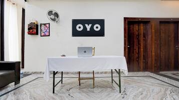 A room with a white table, a laptop, a fan, and a door.