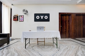 Una habitación con una mesa blanca, una computadora portátil, un ventilador y una puerta.