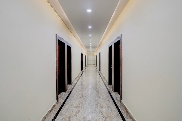 A long, narrow hallway with a marble floor and doors on both sides.