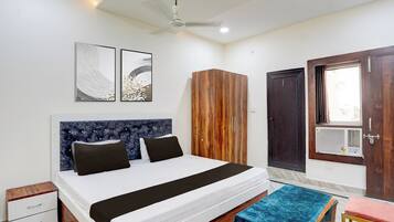 A bedroom with a bed, a wardrobe, a door, and a ceiling fan.