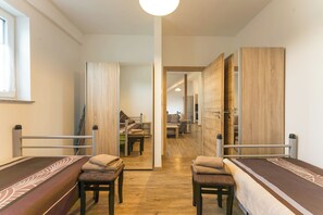 A hotel room with a bed, two chairs, a small table, and a view into the adjacent room. - New Listing (Mainz)