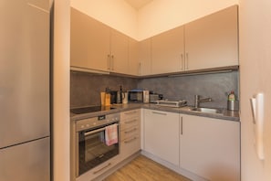 A compact kitchen with a built-in oven, microwave, and a coffee maker. - New Listing (Mainz)