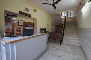 Un espace d’accueil comprenant un comptoir de réception, un ventilateur de plafond et un escalier menant à un niveau supérieur.