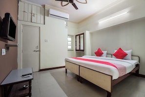 Une chambre d’hôtel équipée d’un lit, d’un bureau avec une chaise, d’une télévision et d’un appareil de climatisation.