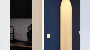 A room with a dark blue wall, a white door, and a mirror.