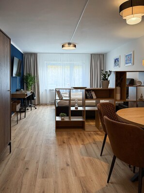 A modern living room with a wooden floor, a round dining table, a sofa, and a coffee table.
