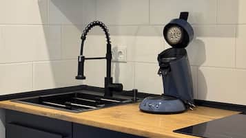 A kitchen with a black faucet, a coffee machine, and a wooden countertop.