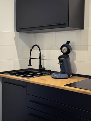 A kitchen with a black faucet, a coffee machine, and a wooden countertop. - Nexpo Executive, Luxury Apartment + Free Parking (Nürnberg)