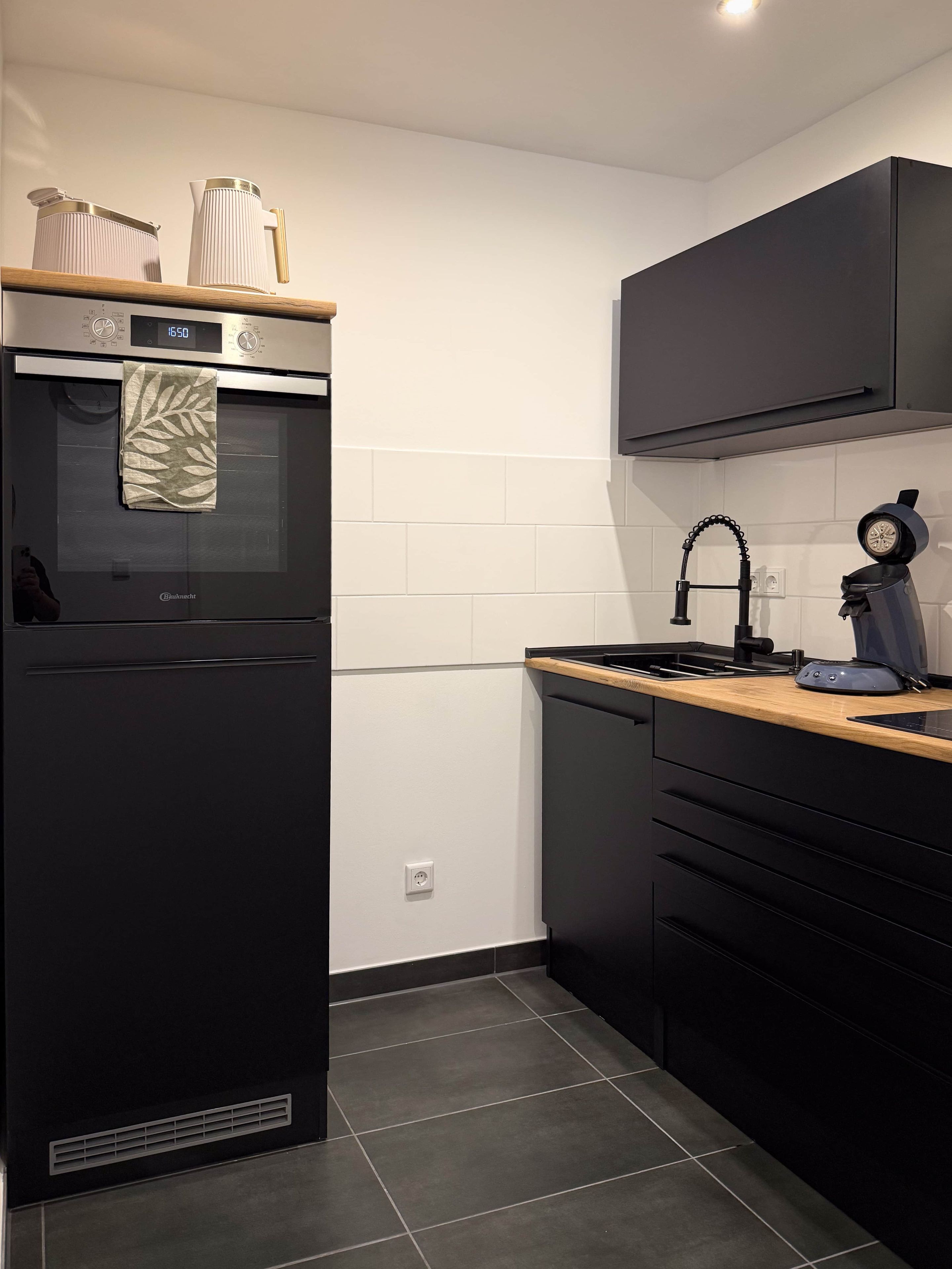 A modern kitchen with a black refrigerator, a stove, and a sink.