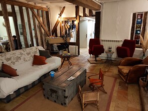 A cozy living room with a sofa, red chairs, a wooden coffee table, and a rustic wooden cabinet. - New Listing (Le Gault-du-Perche)