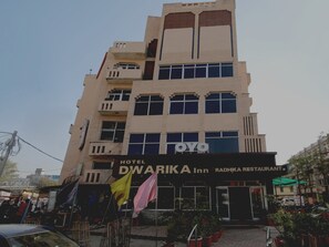 Un immeuble à plusieurs étages, avec une enseigne indiquant « Hôtel Dwarka Inn » et « Restaurant Radhika » au rez-de-chaussée.