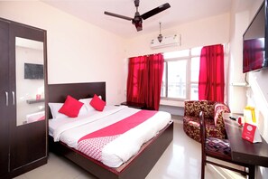 Une chambre d’hôtel équipée d’un lit, d’un bureau, d’une chaise, d’une télévision et d’un ventilateur de plafond.