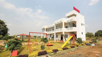 Edificio moderno con un patio de juegos, que incluye columpios y un tobogán.
