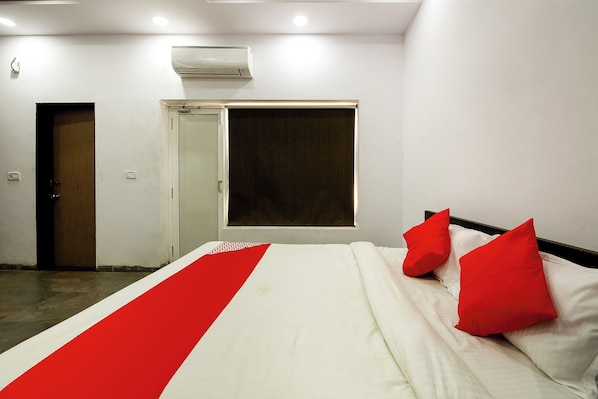 A hotel room with a bed, a window, a door, and an air conditioning unit. - Hotel O Nisarg Resort (Jabalpur)