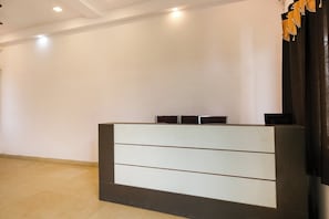 A reception desk with a modern design, featuring a dark base and light upper panels. - Hotel O Nisarg Resort (Jabalpur)