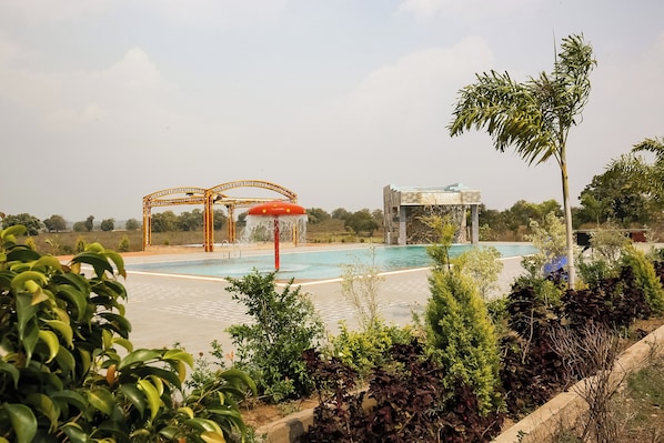 A swimming pool with a water slide and a covered area with a red canopy.