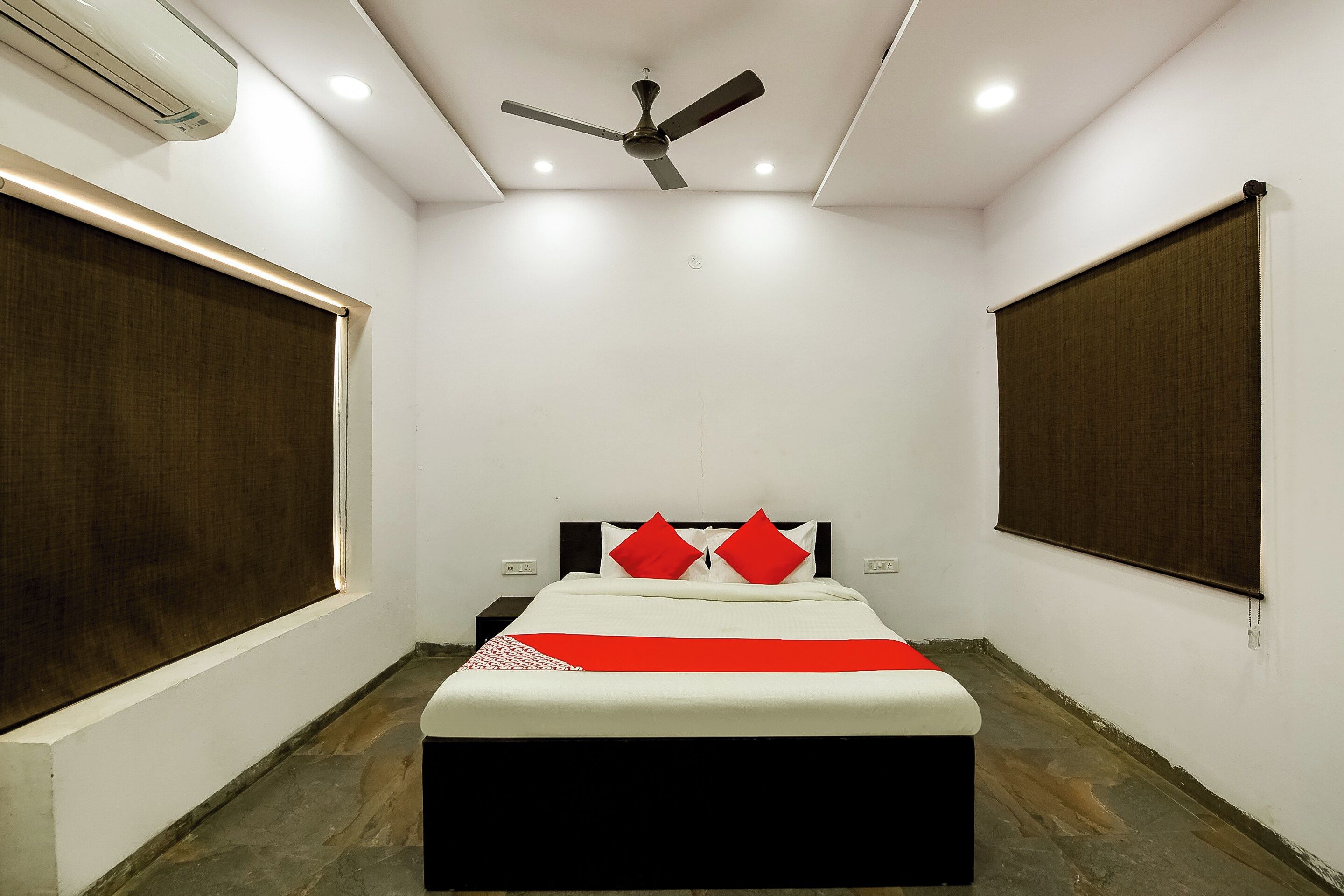 Un dormitorio con una cama, ventilador de techo y aire acondicionado.