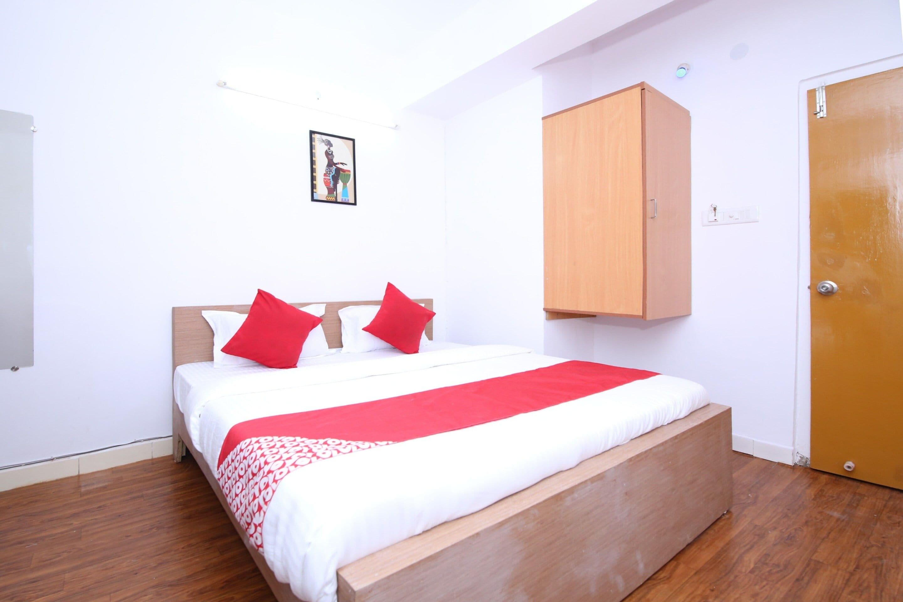 A single-bed room with a wooden headboard, a red and white bedspread, and a wooden wardrobe.