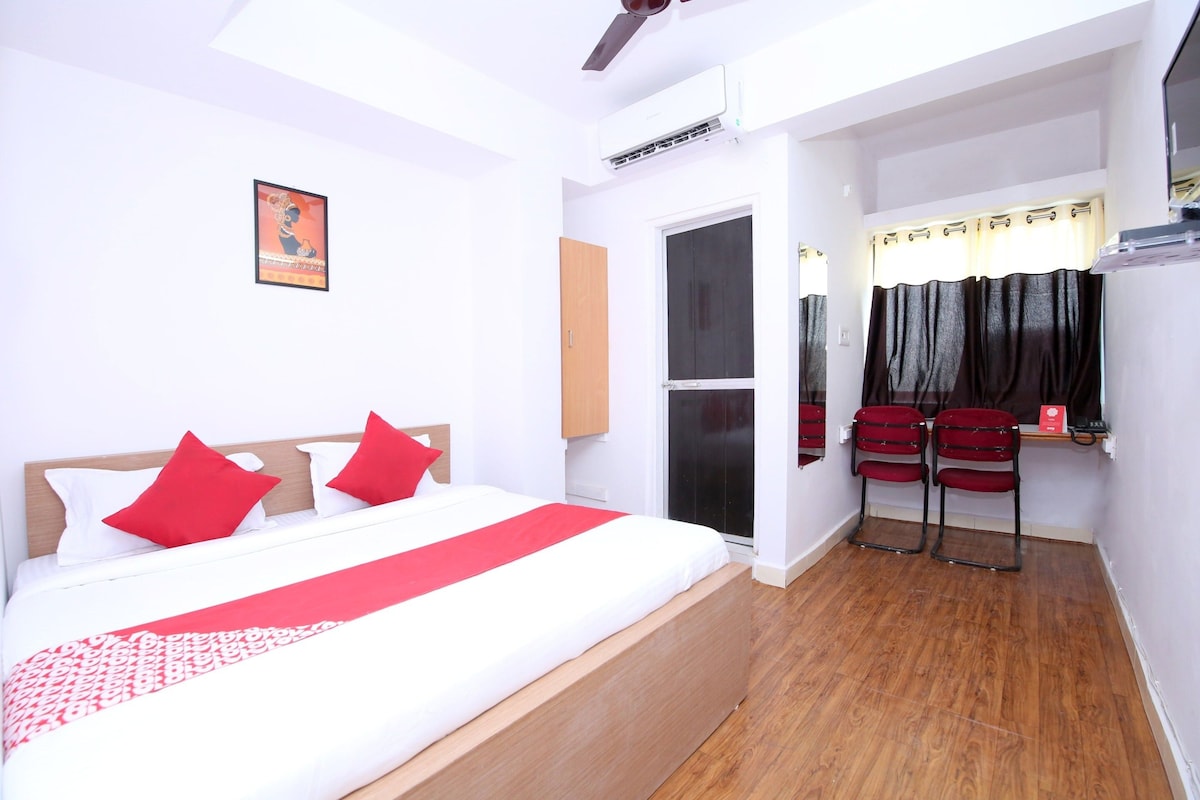 Une chambre d’hôtel avec un lit, un plancher en bois, une fenêtre avec des rideaux et un climatiseur fixé au mur.