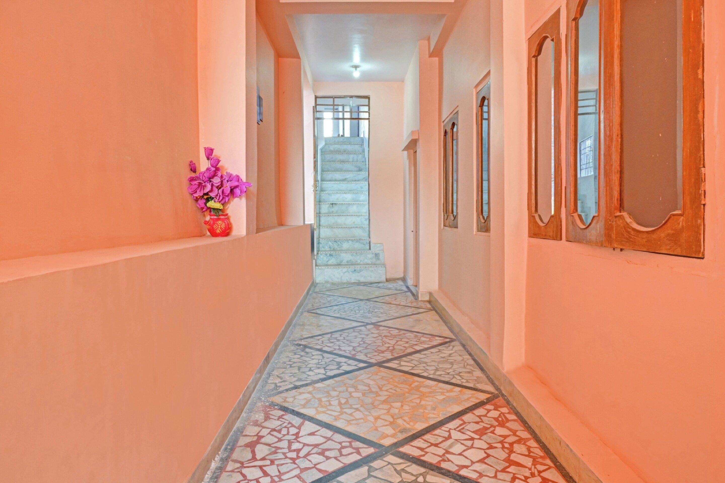 A corridor with a tiled floor leading to a staircase.