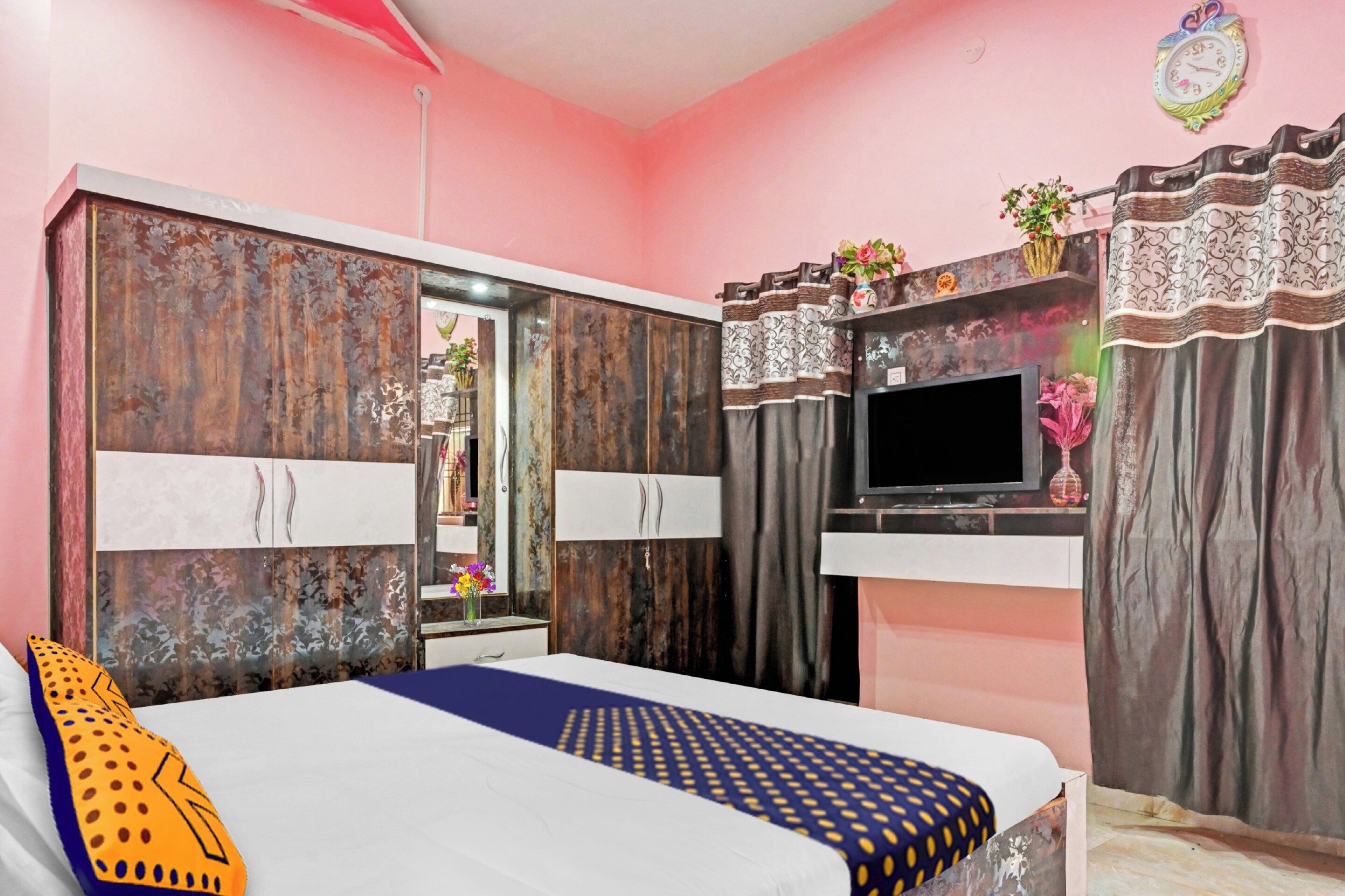 A bedroom with a bed, wardrobe, TV, and decorative items.