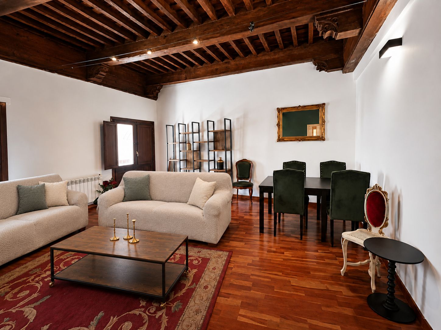 A spacious living room with a wooden ceiling, a sofa set, a dining table with chairs, and a small side table.