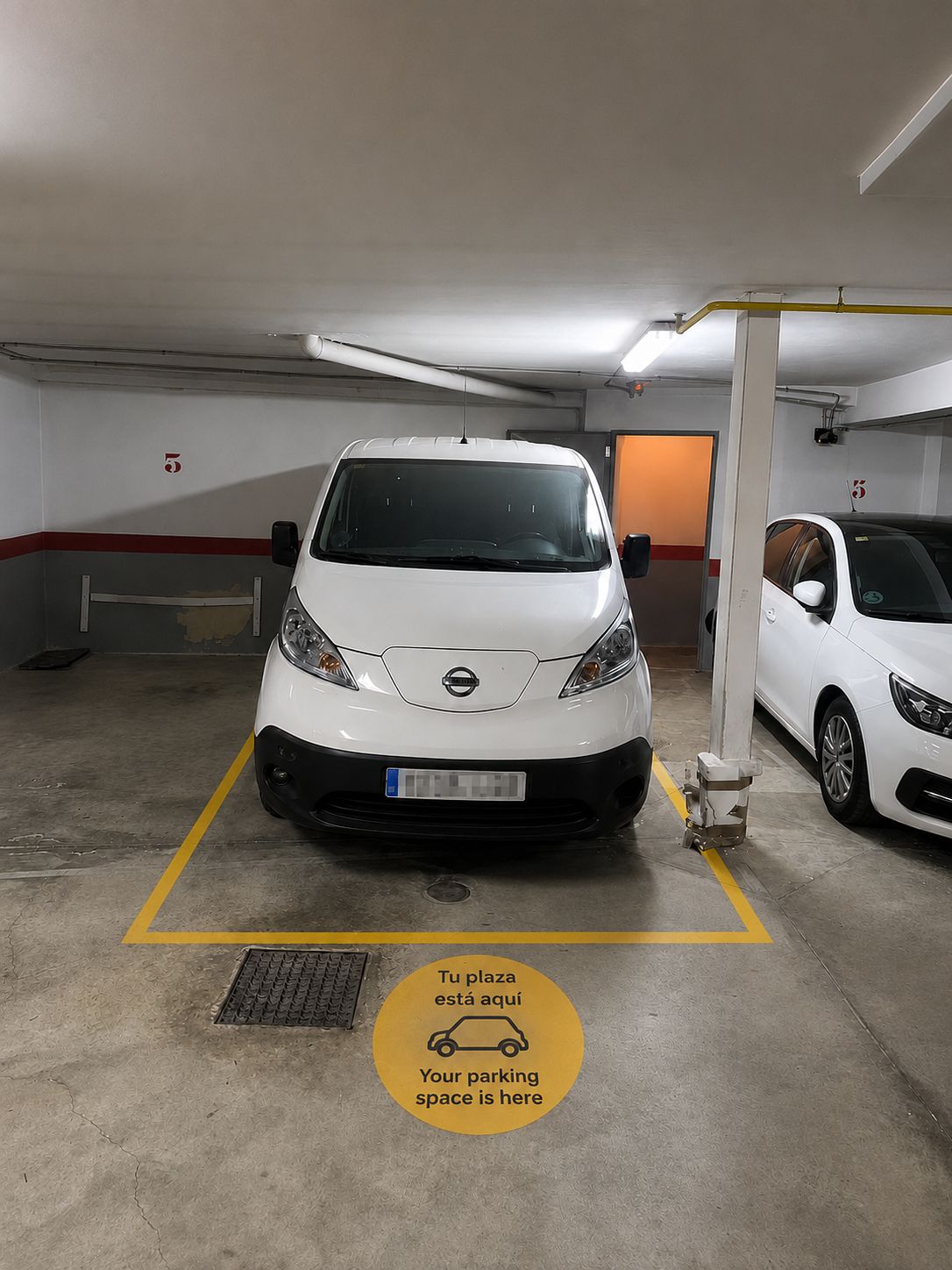 A parking garage with two white cars parked in designated spaces marked by yellow lines.