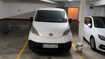 A parking garage with two white cars parked in designated spaces marked by yellow lines.