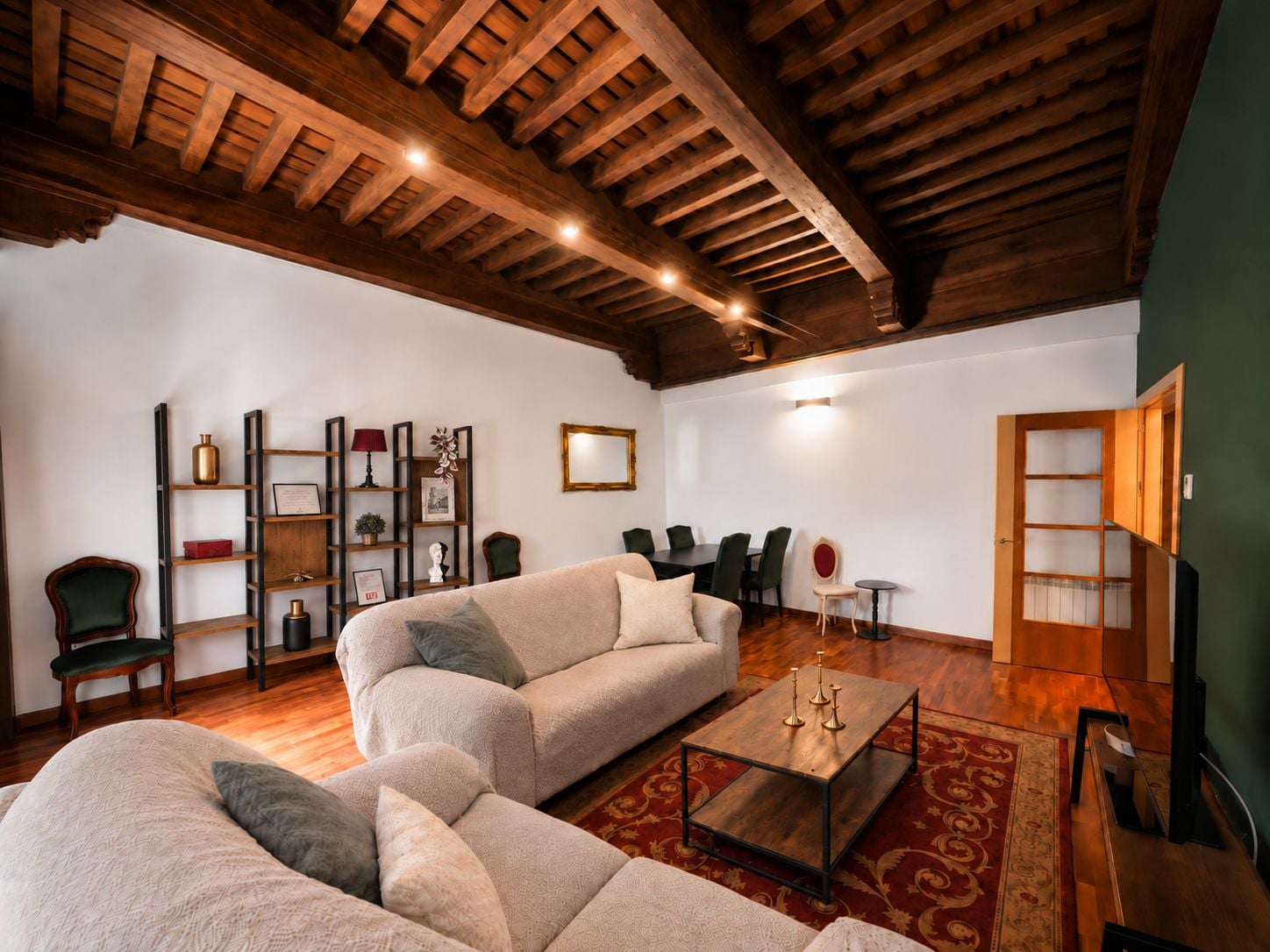 Amplia sala de estar con techo de madera alto, un sofá grande, una mesa de centro y una estantería.