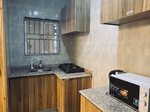 Una cucina compatta con piano di lavoro in granito, lavello in acciaio inossidabile, fornello a gas e forno a microonde.