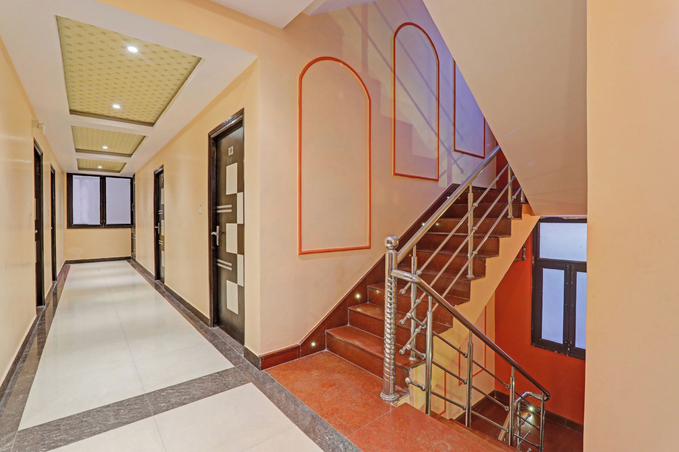 A hotel corridor with a staircase, a door marked with the number 107, and a tiled floor.