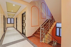 Un pasillo de hotel con una escalera, una puerta marcada con el número 107 y un suelo de baldosas.