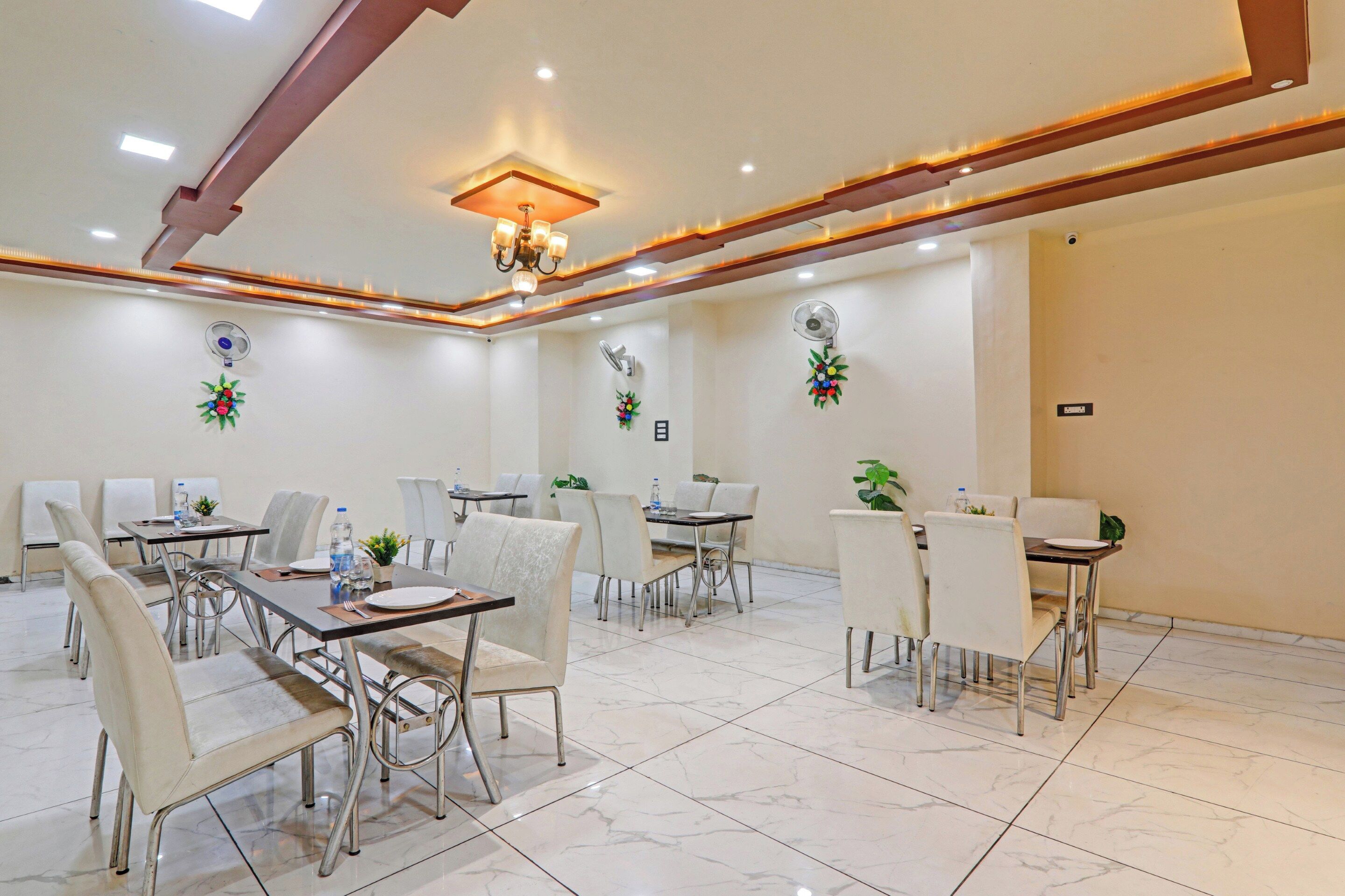 A conference room with tables and chairs, a chandelier, and wall-mounted fans.