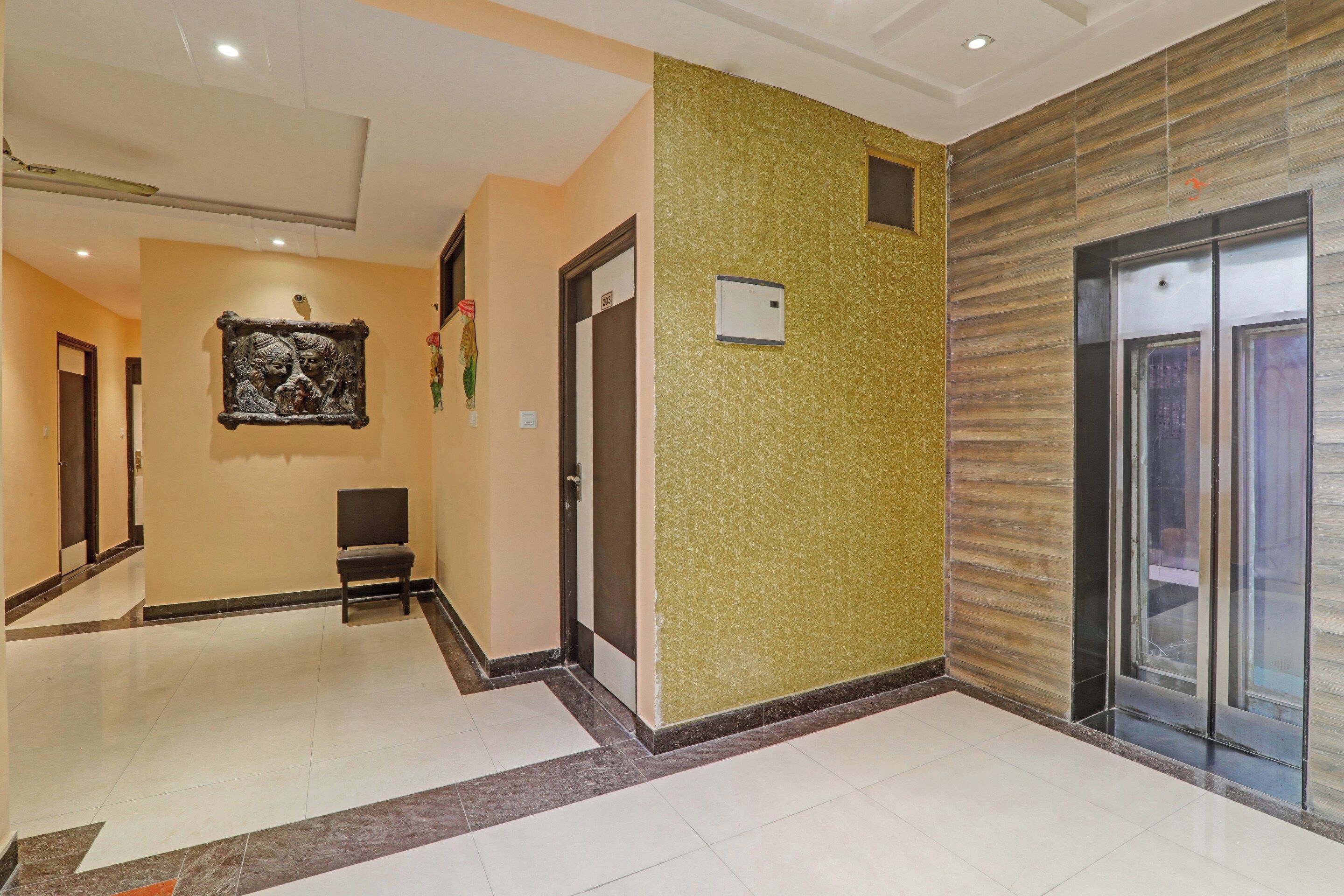 A hotel corridor with a chair, a door with a number, and an elevator.