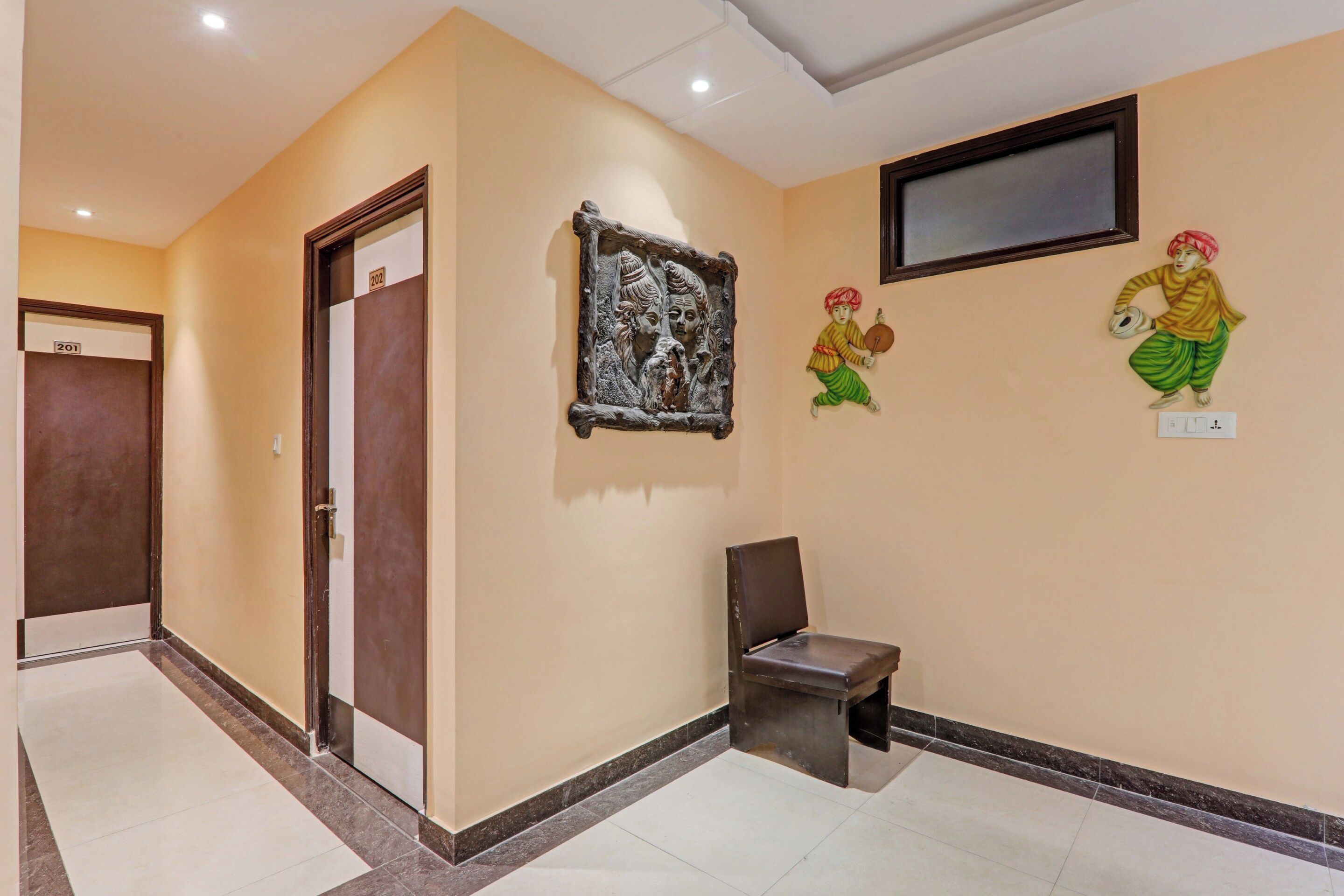 A hallway with a door labeled '201', a wall-mounted TV, and a small bench.