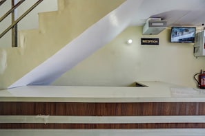 A reception area with a reception desk, a wall-mounted television, and a fire extinguisher. - Hotel O Home Hotel Star Galaxy (Kanpur)