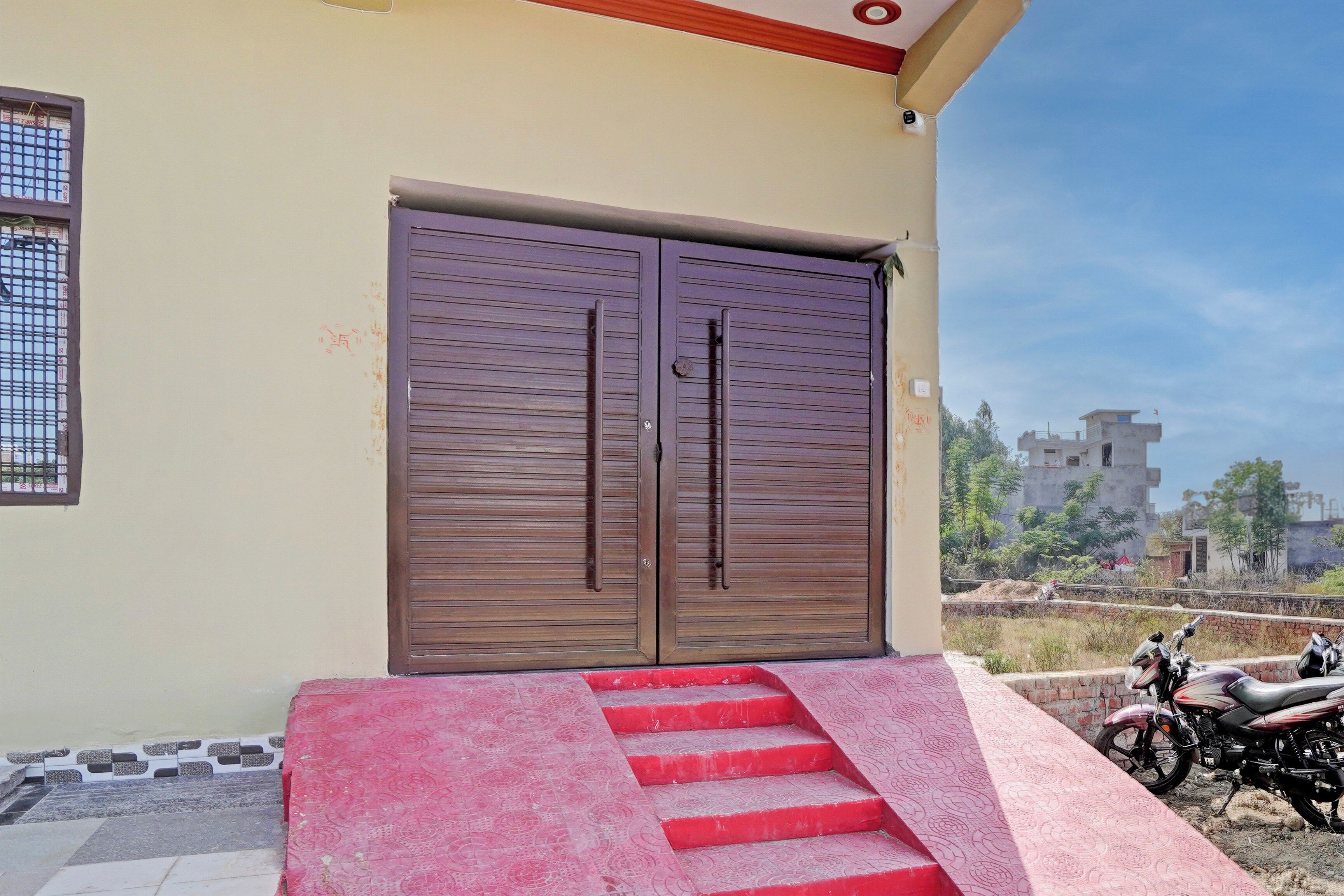 Un edificio con un par de puertas dobles cerradas y una escalera roja que conduce a la entrada.