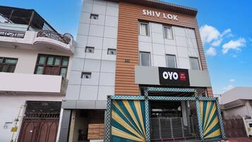 A hotel named Shiv Lok with a modern facade, a prominent sign, and a gated entrance.
