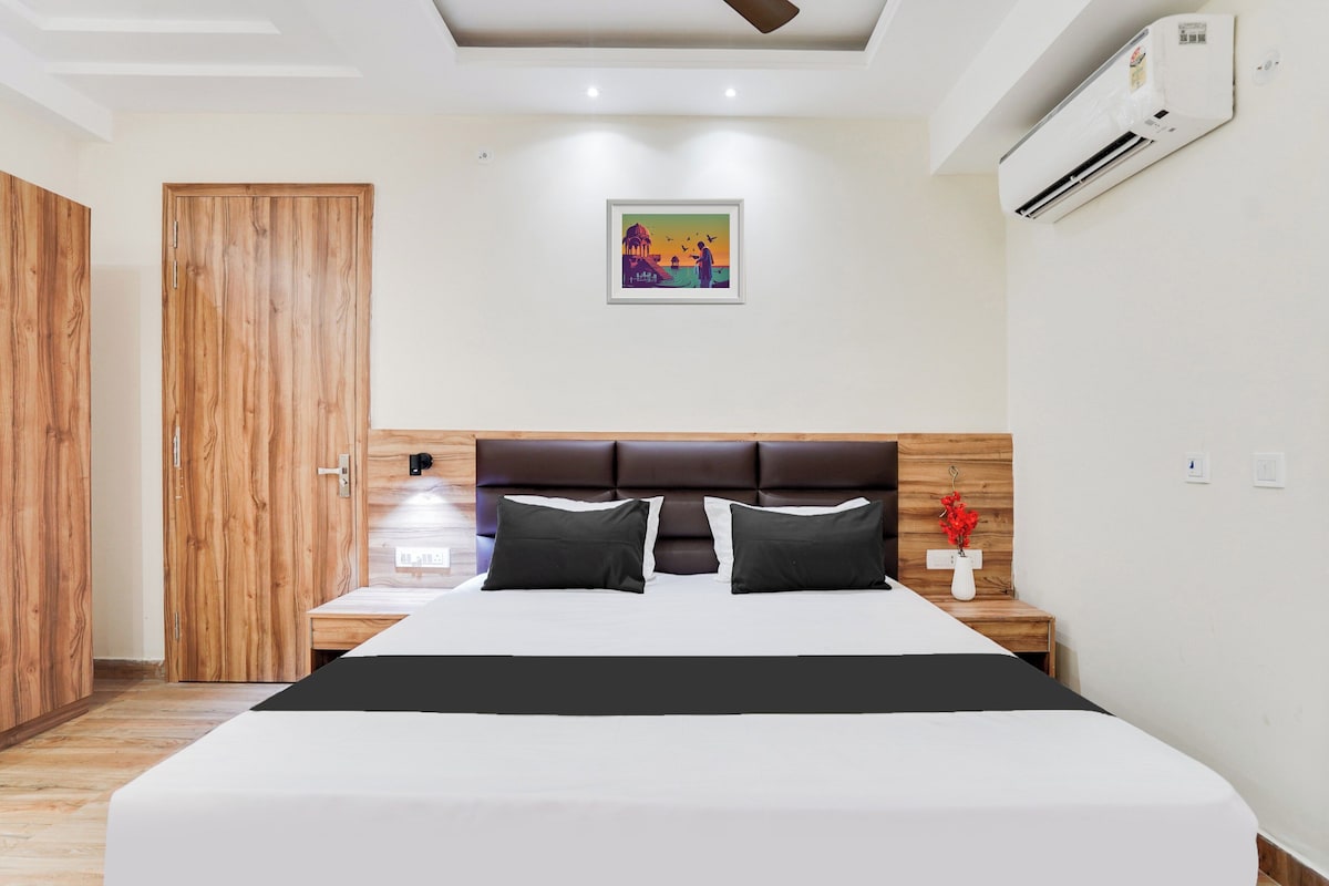 Ein Hotelzimmer mit einem großen Bett, einem Holzschrank, einem Nachttisch mit Blumenvase und einem Deckenventilator.